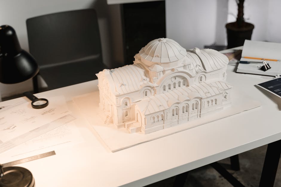A detailed architectural model displayed on a designer's desk with drawing tools and documents.